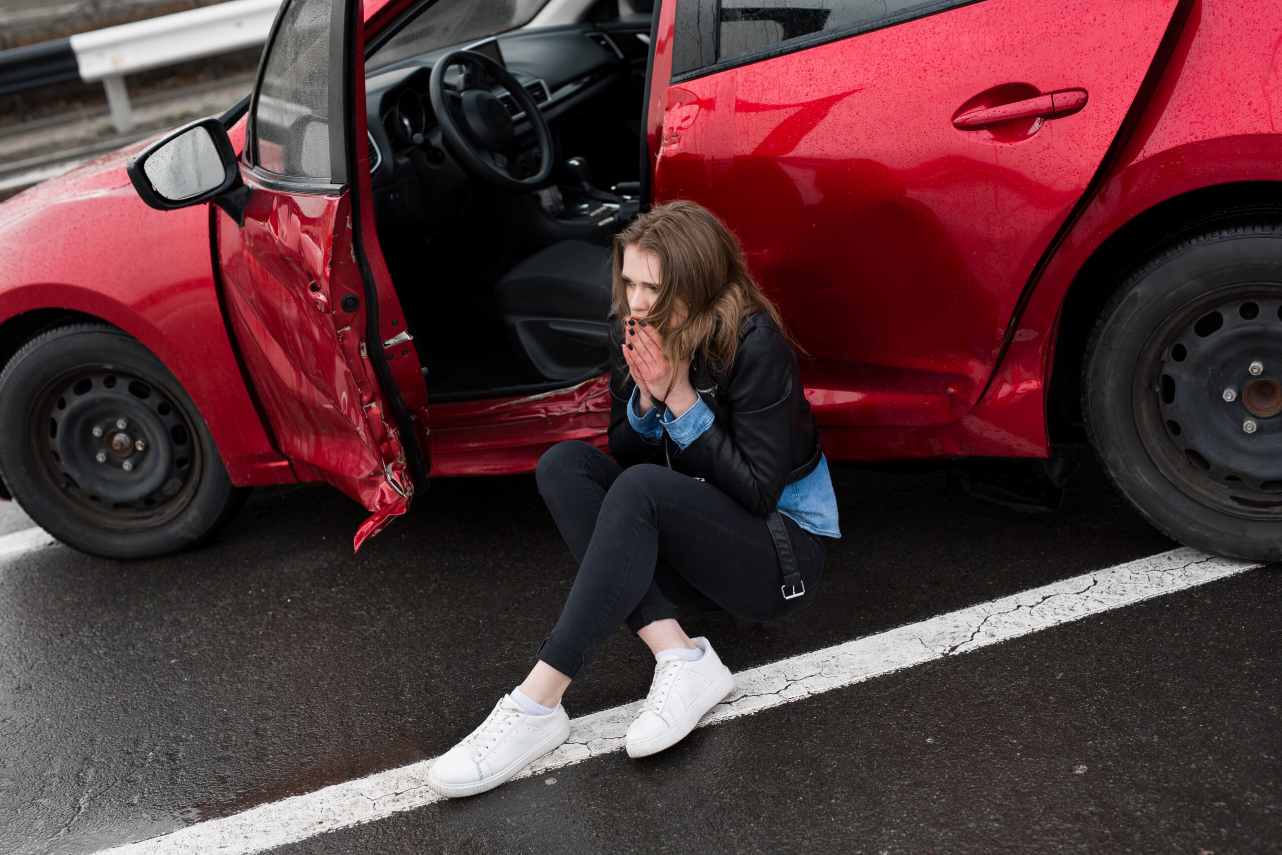 Woman sitting on the roadside after a car accident